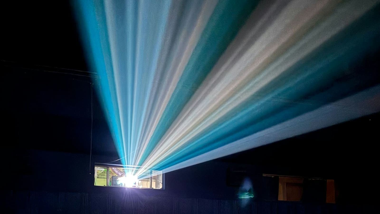 Les faisceaux d'un projecteur traversant la pénombre d'une salle de cinéma vide