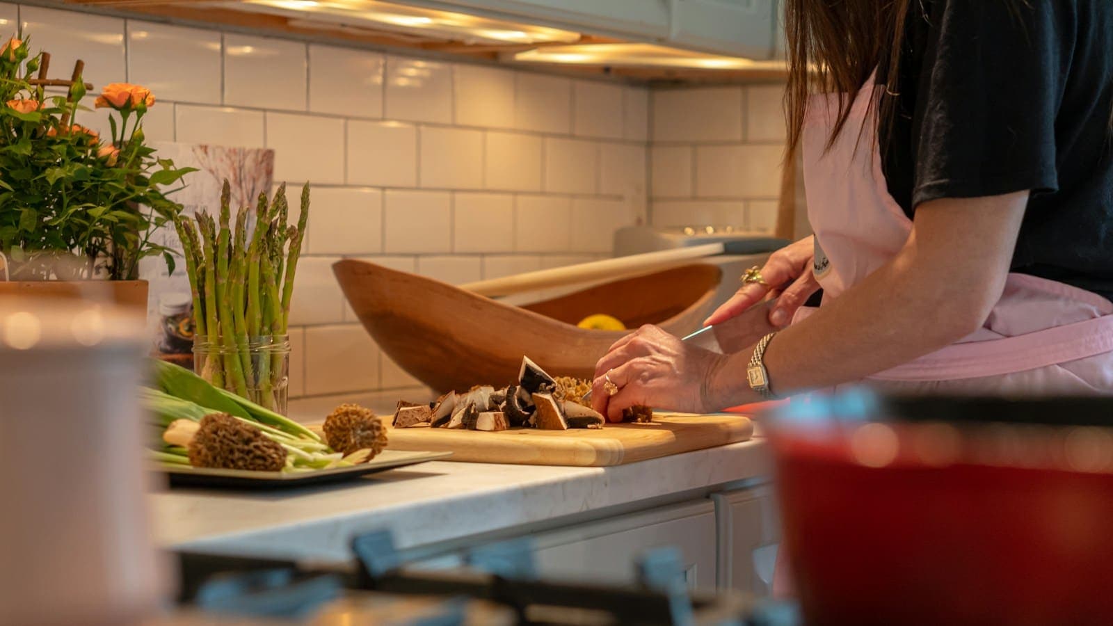 Une personne découpant des légumes sur une planche, dans une cuisine en cours d'utilisation