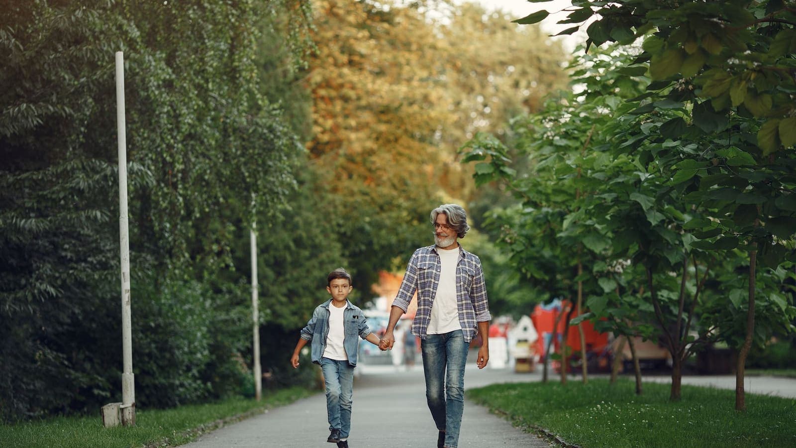 Un grand-parent et un enfant marchant main dans la main dans un parc
